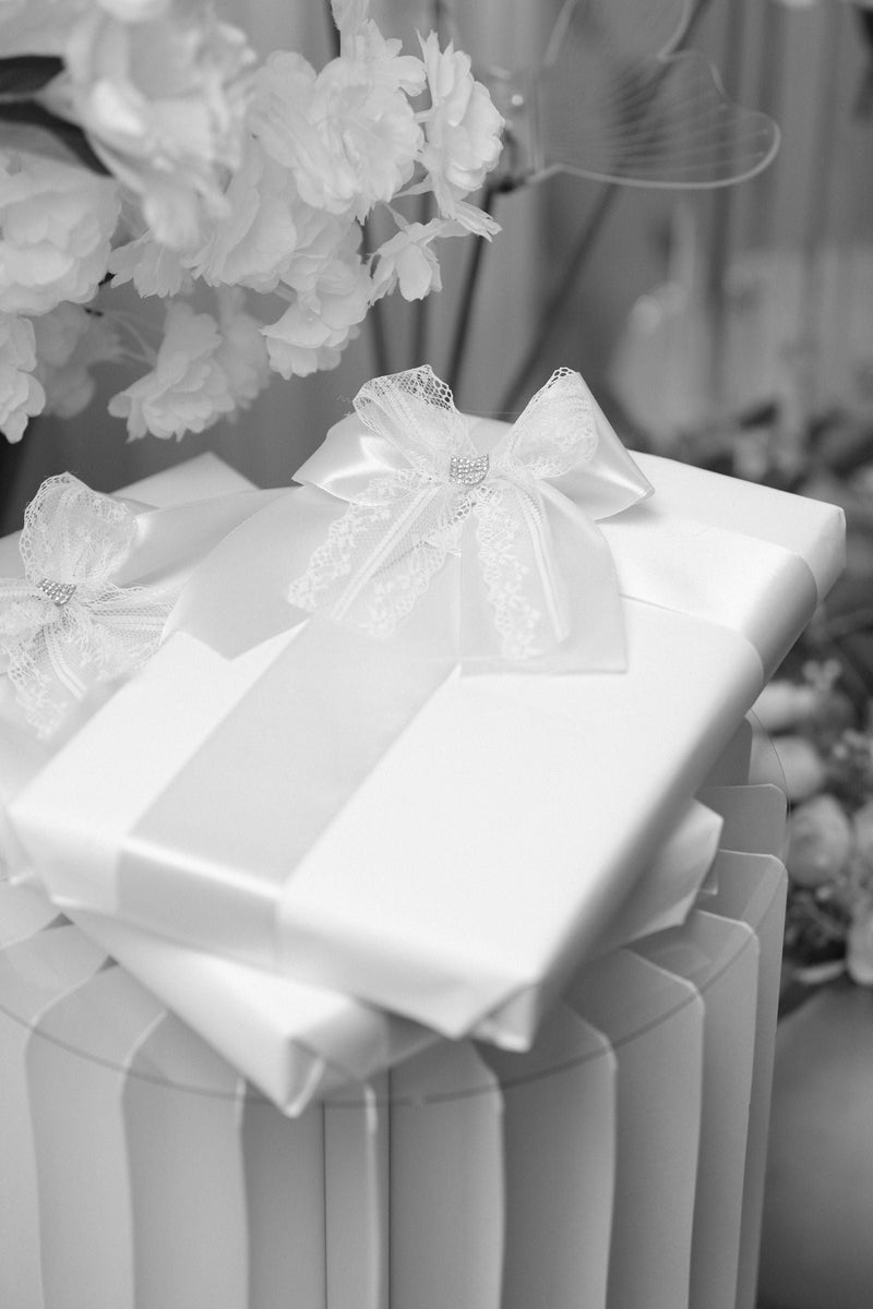 Cadeau pour remercier quelqu'un : un paquet blanc au ruban de satin, posé sur une colonne claire