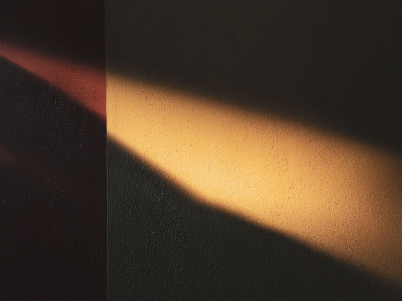 Bande de lumière dorée de fin de journée sur un mur texturé, repère pour savoir combien d'heures par jour diffuser un parfum d'intérieur